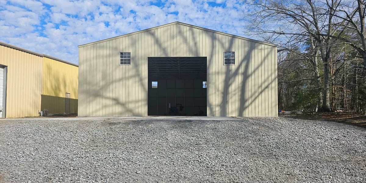 MetBuildings steel building with a roll-up door sitting on a compacted gravel pad