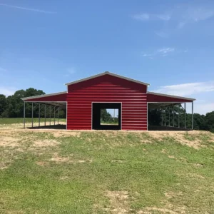 Large red steel barn with open lean-tos on both sides, providing extra covered space. Constructed with galvanized steel for durability and weather resistance.